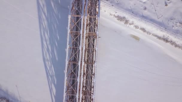 Spoorbrug voor trein verkeer over bevroren rivier op winterlandschap drone weergave. Luchtfoto schorsing trein brug door winter rivier. — Stockvideo