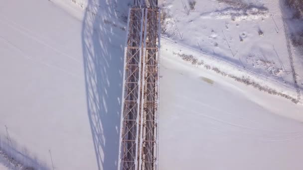 Järnvägsbron för tågtrafik över vintern river på snöiga landskap drönarvy. Hängbro tåg genom vintern river och järnväg spår Flygfoto. — Stockvideo