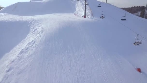 Impianti di risalita per il trasporto sciatori e snowboarder sulle montagne innevate nella località sciistica invernale vista aerea. Seggiovia sci su fune in pista da neve vista drone . — Video Stock