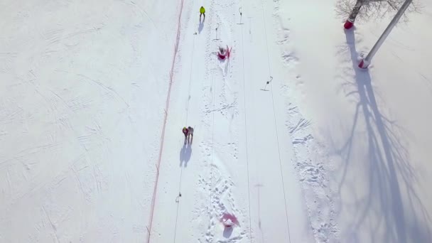 Άτομα που μετακινούνται στο λιφτ του σκι στο χιόνι πλαγιά στο χειμερινό θέρετρο. Ανελκυστήρας σκι στο χιόνι στο βουνό για προβολή μεταφοράς σκιέρ και snowboarders κηφήνας. — Αρχείο Βίντεο