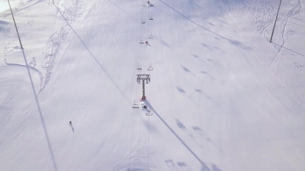 Mensen skiën en snowboarden op de helling van de sneeuw in de winter ski-oord. Skilift op drone mening van de berg van de sneeuw. Winter activiteiten op de ski resort luchtfoto. — Stockvideo