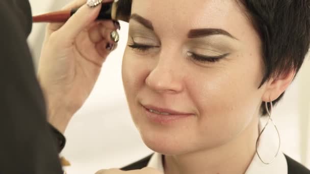 Close up woman face during applying makeup cosmetic with brush on skin in beauty salon. Portrait beautiful woman while make up face in cosmetic salon. — Stock Video