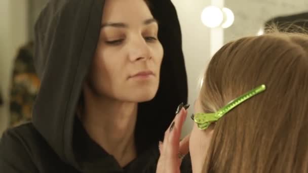 Mujer maquilladora aplicando crema de tono en la cara de la piel modelo de belleza antes de desfile de moda. Primer plano maquillaje mujer cara en vestidor . — Vídeo de stock