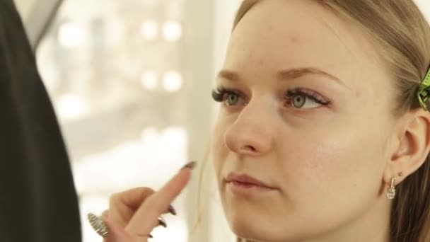 Artista de maquillaje profesional aplicando crema cosmética en la piel problemática mujer joven en el vestidor. Primer plano maquillaje mujer cara en salón de belleza . — Vídeos de Stock