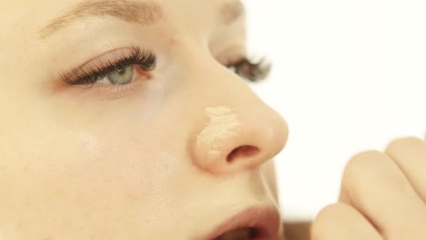 Rostro de mujer joven durante la aplicación de la crema de fundación en la piel en el estudio de maquillaje. Visagiste profesional haciendo maquillaje cara de mujer antes de la foto o video de rodaje en el vestidor . — Vídeos de Stock