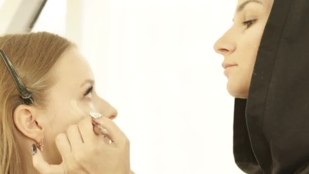 Woman make up artist applying tone cream with cosmetics brush on skin beauty model in dressing room. Professional makeup woman face on lesson during master class in beauty school. — Stock Video