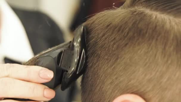 Femme main faisant coupe de cheveux masculins avec tondeuse et peigne dans salon de coiffure fermer. Coiffeur faisant coiffure avec rasoir électrique — Video