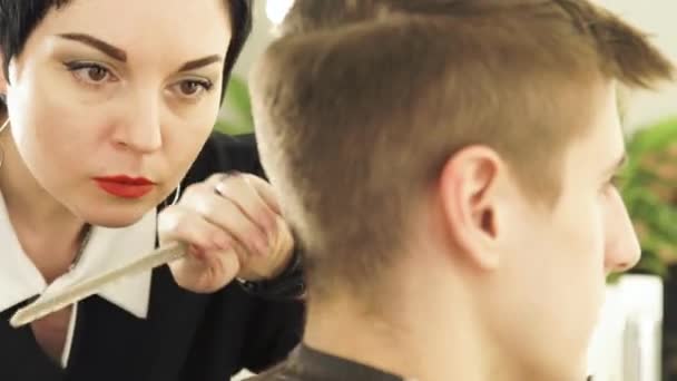 Friseur schneidet männliche Haare mit Elektrorasierer in Schönheitsschule. Frau Friseur macht männlichen Haarschnitt mit Haarschneidemaschine in Friseursalon Nahaufnahme. — Stockvideo