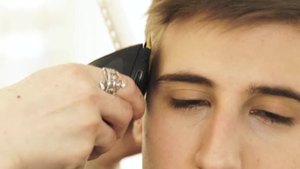 Hombre guapo cara durante el corte de pelo con afeitadora eléctrica en la peluquería. Cierre de corte de cabello con máquina para el cabello. Peluquería hombre con trimmer eléctrico . — Vídeos de Stock