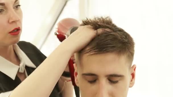 Peluquero secando el cabello masculino después de la peluquería en la peluquería. Cerrar peluquería peinado con secador después de lavar y cortar. Terminar la peluquería en el salón de belleza . — Vídeo de stock