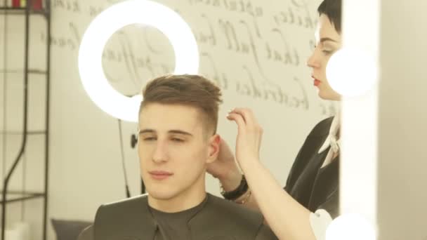 Parrucchiere donna finitura taglio di capelli dopo specchio frontale parrucchiere in studio di bellezza. Close up haircutter facendo acconciatura maschile durante il lavoro con il cliente nel salone di parrucchiere . — Video Stock