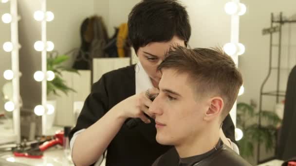 Barber making male haircut with electric shaver in barber shop. Close up hairdresser cutting hair with hair machine in beauty studio. Man hairdressing with electric razor. — Stock Video