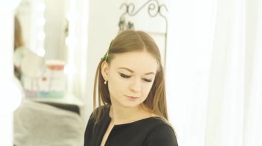 Genç kadın portre saç makyaj soyunma odasında sırasında kelepçe ile. Yüz makyaj modeli ön ayna güzellik okulunda eğitim.