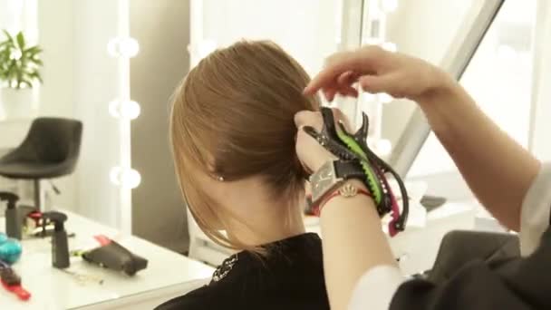 发型师在美发沙龙准备女性理发时使用发夹。关闭美发师工作与女性客户在美容工作室. — 图库视频影像
