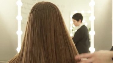 Kuaför kadın saç modeli ön ayna güzellik salonunda yapmak için uzun saç tarama. Güzellik salonda kadın saç modeli kapatın.