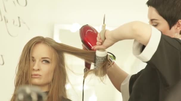 Mulher bonita durante o penteado cabelo longo com secador e escova de cabelo no salão de beleza. Close up haircutter secagem mulher cabelo com secador e pente após a lavagem e corte no salão de cabeleireiro . — Vídeo de Stock