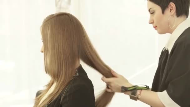 Cabeleireiro fazendo penteado para cabelos longos depois de cabeleireiro no estúdio de beleza. Close up haircutter acabamento mulher penteado no salão de cabeleireiro . — Vídeo de Stock