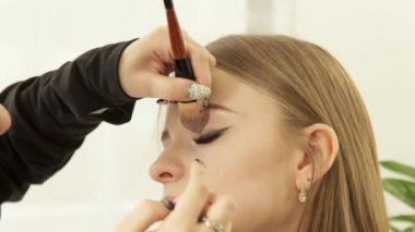 Sanatçı makyaj gözler güzellik okul için kozmetik fırça kullanarak oluşturur. Makyaj yüz genç kadın için yapıyor visagiste kadar kapatın.