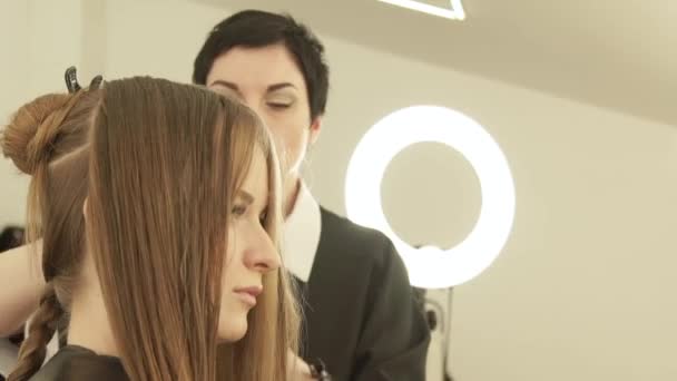 Парикмахер расчесывает женские волосы во время стрижки в салоне красоты. Закрыть парикмахерскую, сделать женскую стрижку в парикмахерской . — стоковое видео