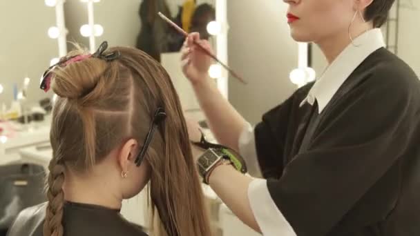Парикмахер расчесывает женские волосы во время стрижки в парикмахерской. Закройте женскую прическу в салоне красоты. Парикмахер работает с клиенткой . — стоковое видео