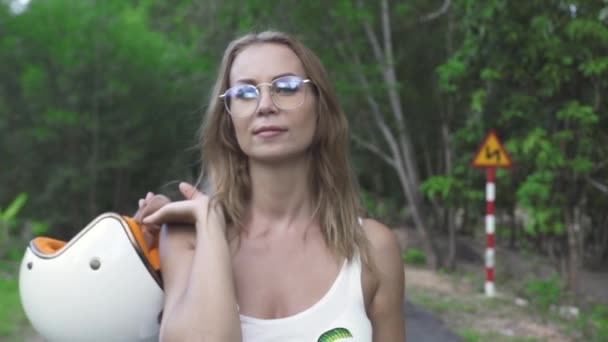 Beautiful and confident middle-aged woman holding a helmet wearing sunglasses. — Stock Video