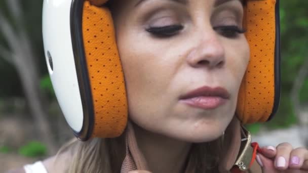 Портрет жінки-мотористки знімає шолом і хвилі волосся вперед і назад . — стокове відео