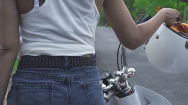 Сексуальная мотоциклистка берет шлем на мотоцикле и идет по дороге . — стоковое видео