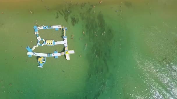 Top down vy flyga över turist och uppblåsbara flytande lekplats på stranden. — Stockvideo