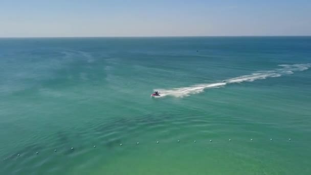 Aerial tracking fly over a tourist in a resort riding a fast jetski on summer. — Stock Video