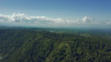 Bir dağ ormanının üzerinden uçmak. Ufukta mavi gökyüzüne karşı güzel bulutlar