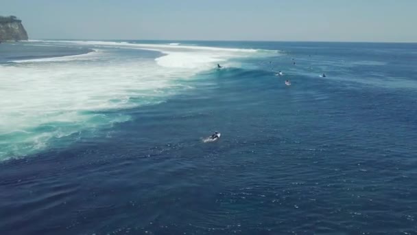 Vue aérienne cinématographique sur un surfeur chevauchant une vague déferlante dans l'océan en été . — Video