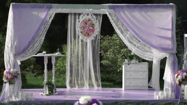 Ein Hochzeitsaltar in den Farben Weiß und Lavendel und weiße Stühle mit rosa Schleifen. — Stockvideo