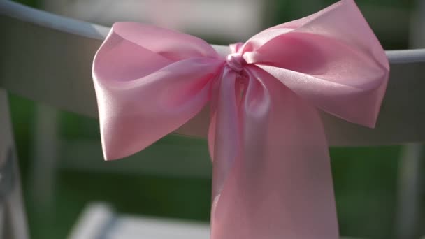 White chairs with pink bows waving in the wind closeup. Focus moves from one to the other bow. — Αρχείο Βίντεο