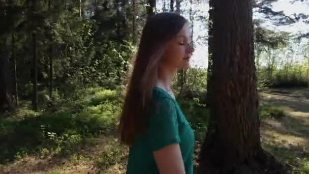 Schöne Mädchen in einem grünen Kleid spaziert sonnigen Sommertag im Wald. — Stockvideo