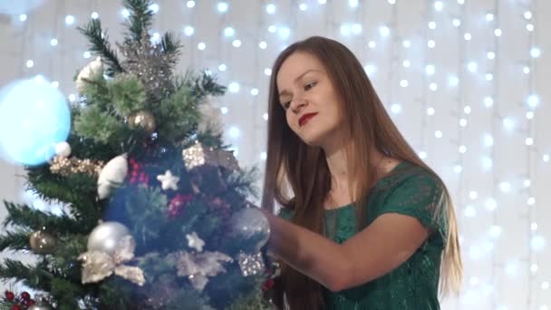 Mujer sexy juguetona con lápiz labial rojo viste el árbol de Navidad, admirando los juguetes, sonrisa linda, endereza los juguetes — Vídeo de stock