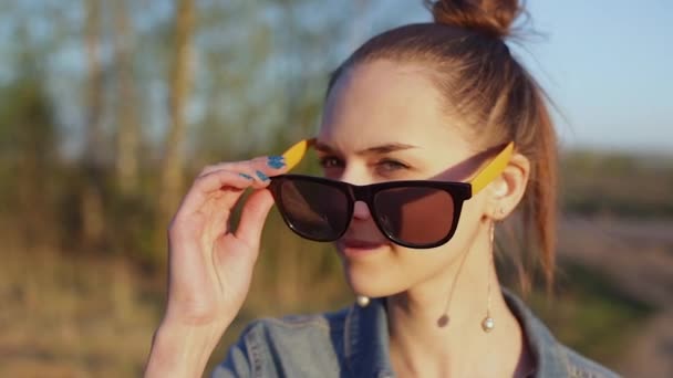 Молода, стильна, неформальна дівчина дивиться навколо, знімає сонцезахисні окуляри . — стокове відео