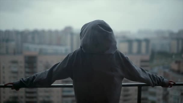 Meisje staande op het balkon in de regen-uitzicht vanaf de achterkant — Stockvideo