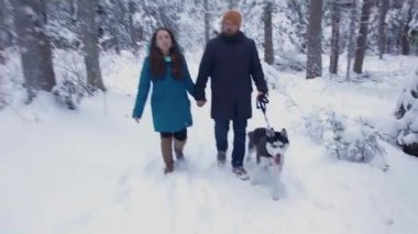 Husky köpek ile bir kış ormandaki elele çift yürür