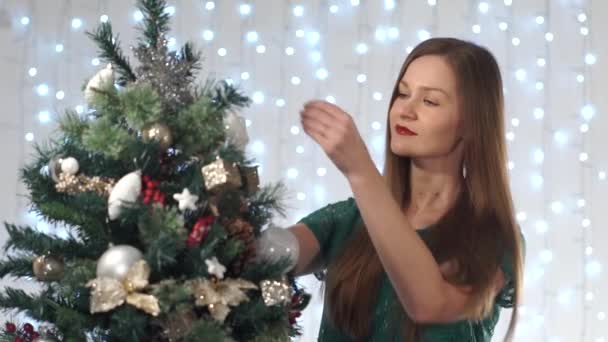 Speelse sexy vrouw met rode lippenstift aankleedt kerstboom, bewonderen de speelgoed, schattige glimlach, geniet van het proces — Stockvideo