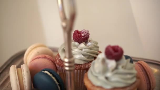 Muffins de chocolate com framboesas e macaroon multicolorido em uma barra de doces, close-up — Vídeo de Stock