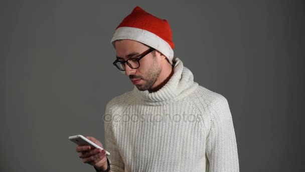 Hombre brutal serio en gafas y una gorra roja de Santa Claus llamando por teléfono y está enojado porque no hay diales — Vídeos de Stock