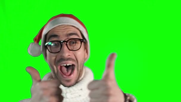 Schöner junger Mann mit stylischer Brille und Weihnachtsmann-Hut reicht den Daumen in die Kamera und lächelt — Stockvideo