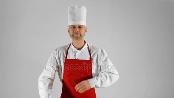 Красивий дорослий шеф-кухар повертається, він перехрещує руки і киває голову на сірому фоні — стокове відео