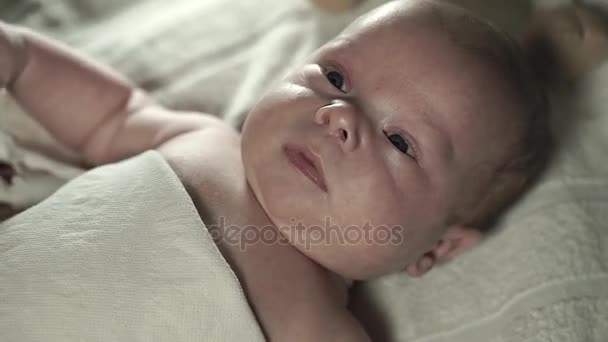 毛布の下のベッドの上に横たわる魅力的な赤ちゃん。母はそれをストロークします。. — ストック動画