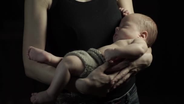Jonge moeder stenen slaap van een kind in haar armen. Een donkere kamer. — Stockvideo