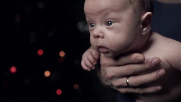 Papa tient le bébé dans ses bras. L'enfant bouge activement . — Video