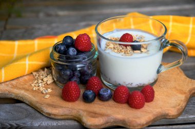Sağlıklı bir kahvaltı yapıyorum. Yoğurt, granola, chia tohumu, taze ve kuru meyve, yaban mersini, şeffaf ahududu. Temiz yemek, diyet, detoks, vejetaryen gıda konsepti.
