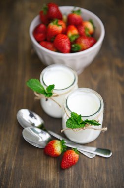 Ahşap bir masada chia ile iki bardak yoğurt nane ve çilekle süslenir..