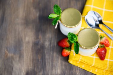 Ahşap bir masada iki bardak doğal yoğurt naneli ve çilekli..