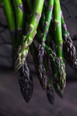 Tahta masadaki sepette bir sürü taze kuşkonmaz. Fotoğraf seçici bir odak ile çekildi.